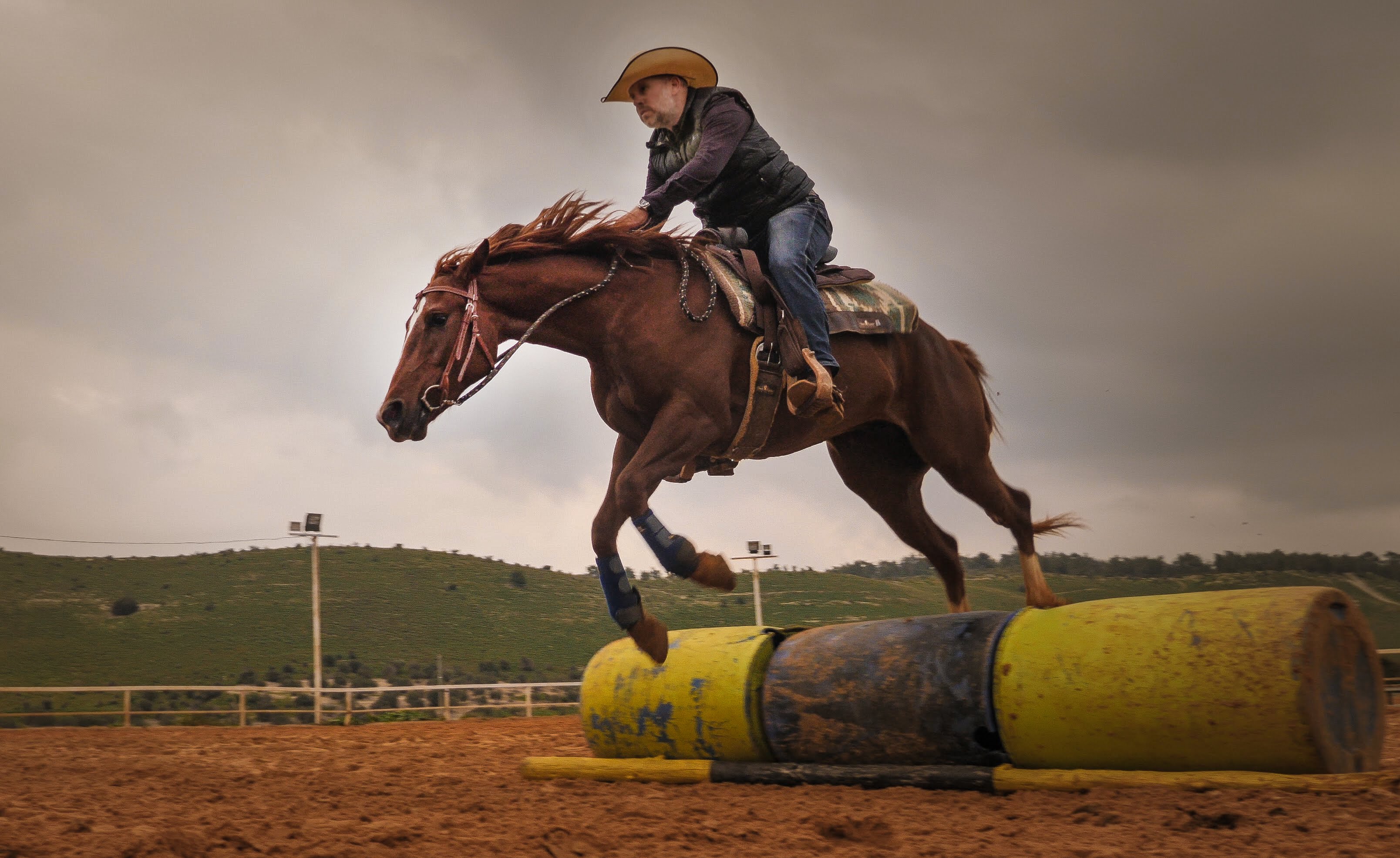 Omri Livny riding a horse over barrels